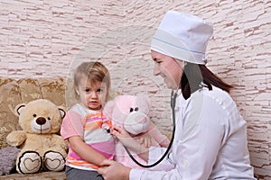 Female doctor is listening to child with stethoscope at home