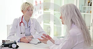 Female doctor listens, elderly woman talks about chronic diseases health complaints symptoms of ailment