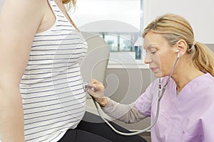 female doctor listens pregnant belly