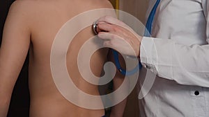 A female doctor listens to the breath of a child using a stethoscope. Medical examination of the child. Health concept