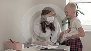 A female doctor listens to a stethoscope of a cheerful teenager boy