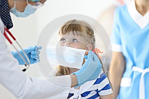 Female doctor with little child put on protective mask portrait photo