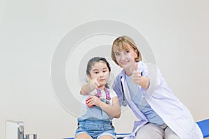 Female doctor and little cute girl showing thumbs up. Kid on consultation at the pediatrician. Healthcare and medicine concepts