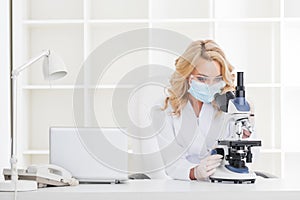 Female doctor looking through a microscope