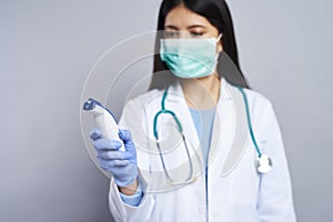 Female doctor looking at non-contact thermometer