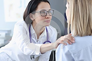 Female doctor looking at patient and holding her shoulder