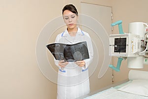 Female doctor looking at patient spinal x-ray in radiologist`s cabinet