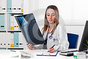 Female doctor looking at patients x-ray in her office