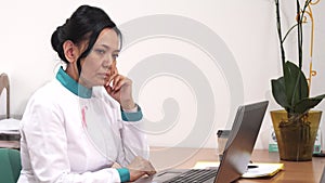 Female doctor looking upset receiving bad news working on the laptop at her clinic