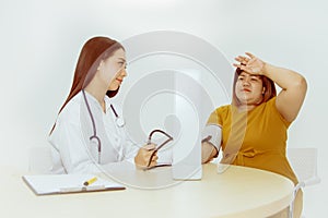 Female doctor looks at an obese female patient who has a headache and is sick during treatment to a doctor at the hospital with co