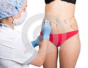 Female doctor makes dotted line on female body for cellulite correction. cosmetic surgery. lifting and breast