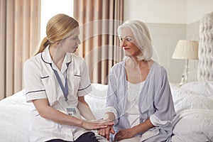 Female Doctor Making Home Visit To Senior Woman For Medical Check Offering Reassurance photo