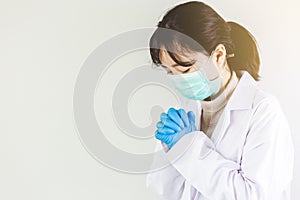 Female doctor in maks with stethoscope praying. photo