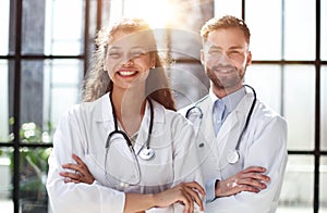 a female doctor and a male doctor are standing in the office with their arms crossed