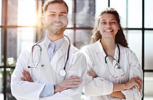 a female doctor and a male doctor are standing in the office with their arms crossed