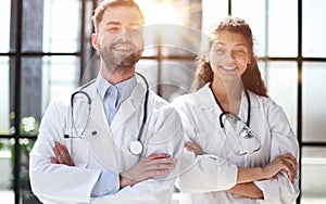 a female doctor and a male doctor are standing in the office with their arms crossed