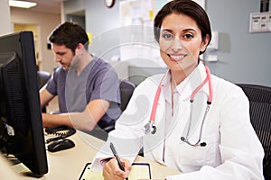 Female Doctor With Male Nurse Working At Nurses Station