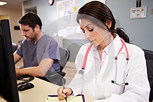 Female Doctor With Male Nurse Working At Nurses Station