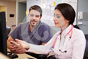 Female Doctor With Male Nurse Working At Nurses Station