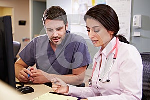 Female Doctor With Male Nurse Working At Nurses Station