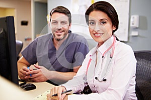 Female Doctor With Male Nurse Working At Nurses Station photo