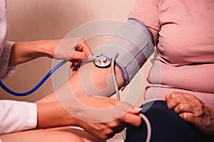 Female doctor measures woman`s blood pressure with tonometer