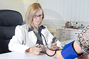Female Doctor Measuring Blood Pressure of a Patient in Consulting Room