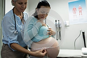 Female doctor measuring pregnant woman belly