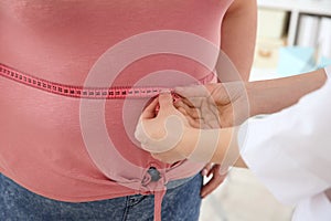 Female doctor measuring waist of overweight woman