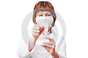 A female doctor in a medical mask holds a syringe
