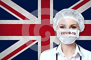 Female doctor in medical mask with the inscription COVID-19 on a blurred background of the flag of Great Britain. Pandemic virus