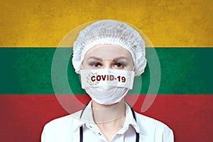 Female doctor in medical mask with the inscription COVID-19 on a blurred background of the flag of Lithuania. Pandemic virus COVID