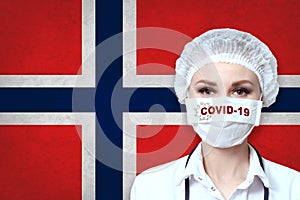 Female doctor in medical mask with the inscription COVID-19 on a blurred background of the flag of Norway. Pandemic virus COVID-19