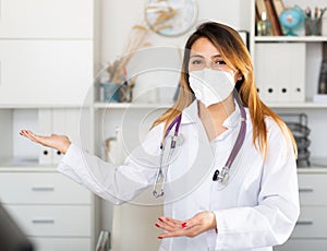 Female doctor in medical mask inviting to doctor& x27;s office