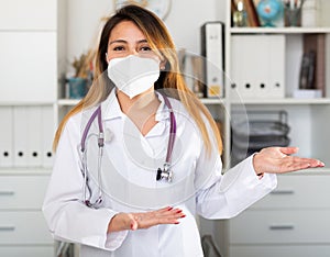 Female doctor in medical mask inviting to doctor's office