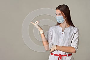 A female doctor in a medical mask points to an empty place, copy space