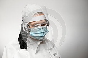 Female doctor in medical protective clothing and black latex glove holds phone near her ear