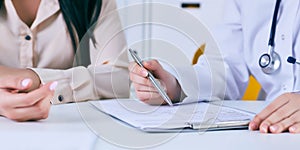 Female doctor meeting with a patient in the office, she is giving a prescription to the woman. Just hands over the table