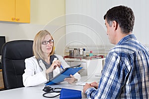 Female Doctor and Middle Aged Patient Talking in Consulting Room