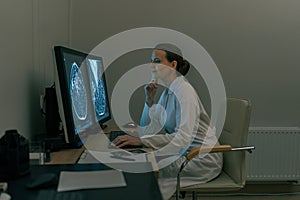 Female doctor neuroscientist analyzing brain scan MRI images in hospital