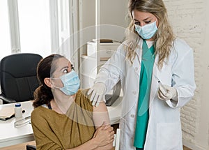 Female doctor or nurse giving shot or vaccine to a patient. Vaccination and prevention concept