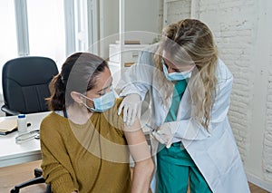 Female doctor or nurse giving shot or vaccine to a patient. Vaccination and prevention concept