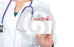 Female doctor or nurse holding and showing blank empty business card