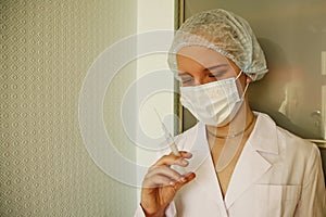 Female Doctor Or Nurse In Mask Holding Syringe