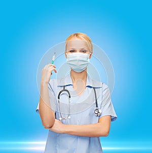 Female doctor or nurse in mask holding syringe