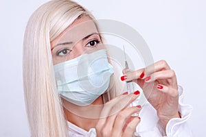 Female doctor or nurse in medical mask holding syringe with injection