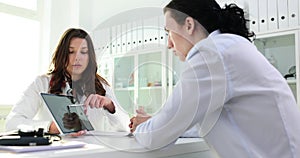 Female doctor or nurse showing digital tablet to male patient in clinic