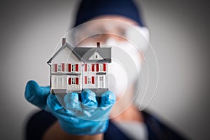 Female Doctor or Nurse Wearing Surgical Gloves Holding Model Home