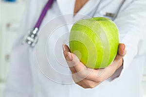 Female doctor offering green apple