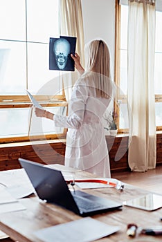 Female doctor in office looks at X-ray.